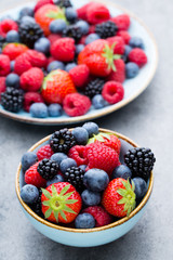 Fresh berry salad on blue dishes. Vintage wooden background.
