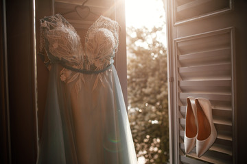 White shoes and wedding dress hang on the open window