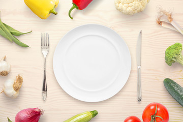 Empty plate surrounded with organic fresh vegetables. Top view composition.