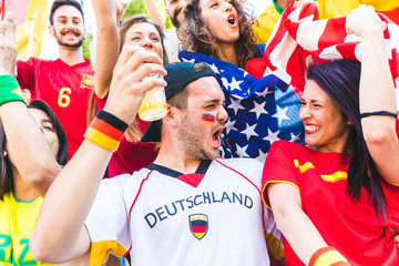 Fototapeta premium International couple of fans celebrating together at stadium during a match