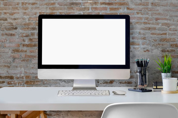 Mockup blank screen desktop computer on white desk over wall in studio office.