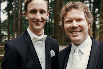 Two handsome groomsmen pose in the forest