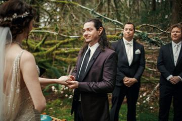 Groom looks at bride with love holding her hand before a wedding altar