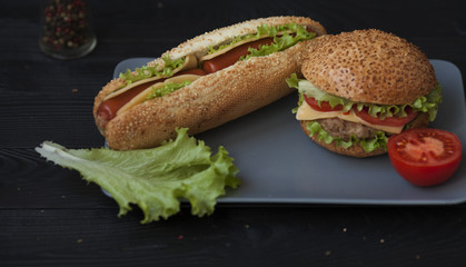 Hotdog with big sausage and fresh tomato. Delicious fresh homemade burger on a wooden table