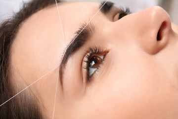 Young woman having professional eyebrow correction procedure, closeup