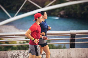 Happy couple running across the bridge. Healthy lifestyle.