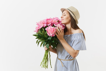 Young tender woman in blue dress, hat holding, sniffing bouquet of pink peonies flowers isolated on white background. St. Valentine's Day, International Women's Day holiday concept. Advertising area.