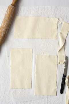 Three rectangular pieces of pastry with a rolling pin and knife