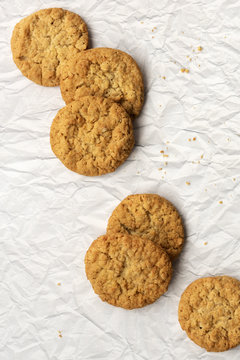 Six honey and oatmeal biscuits on a textured paper background.
