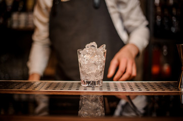 Beautiful ornate glass full of ice standing on the bar counter