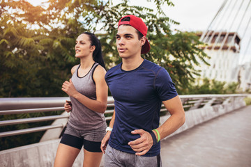 Happy couple running across the bridge. Healthy lifestyle.