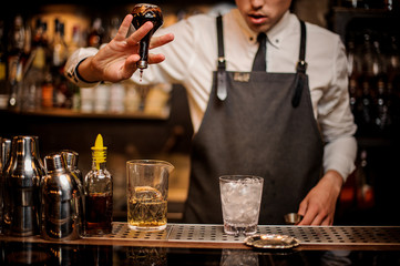 Fototapeta na wymiar Brunet bartender adding an alcoholic essence into the mixing glass