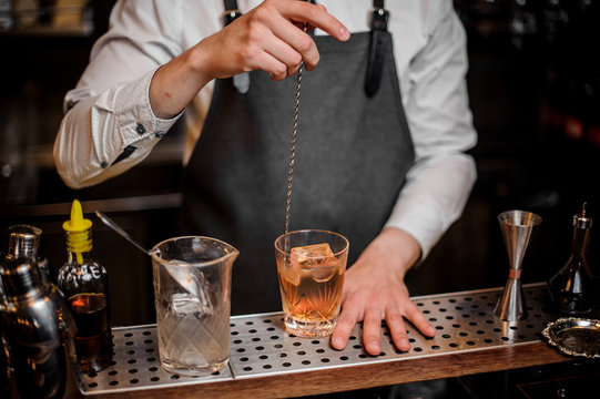 Bartender stirring cocktail in the ornate glass on the bar counter