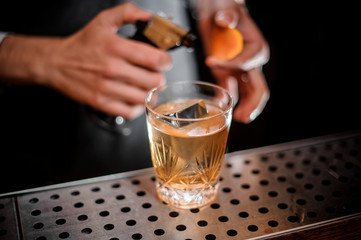 Bartender ready to fire an orange zest and adding it to the fresh alcoholic drink