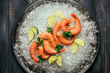 Shrimp with ice with lime and salad on the plate. On wooden background