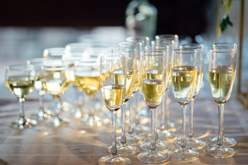 A lot of wine glasses with a cool delicious champagne or white wine at the bar. Alcohol background.