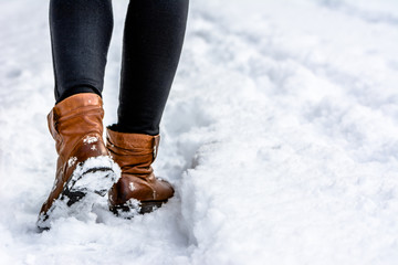 Brown boots in snow, woman put the step in snow, walking in winter