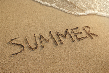 Inscription on a wet sand (Summer) with sea waves on a sunset, top view.