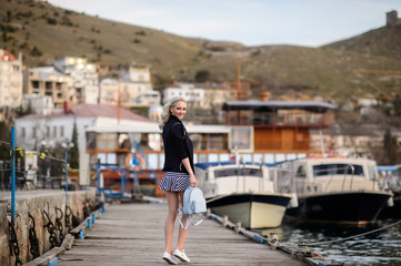 Beautiful girl outdoors. Spring day. The girl near boats on a marina.