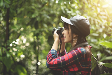 Asian girl traveler in red plaid shirt taking photo.