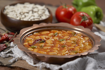 Dried beans,white beans in tomato sauce in a copper bowl closeup. horizontal
