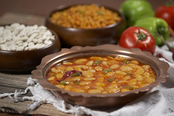 Dried beans,white beans in tomato sauce in a copper bowl closeup. horizontal
