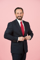 Portrait of styled man isolated in studio. Man in suit and red tied fasten jacket. Happy businessman fasten button on jacket of blue suit