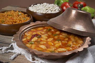 Dried beans,white beans in tomato sauce in a copper bowl closeup. horizontal

