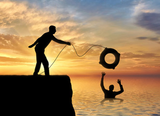 A silhouette of a man throws a lifeline to another man who is drowning in the water - obrazy, fototapety, plakaty