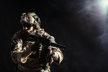 Special forces soldier with rifle on dark background