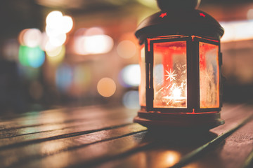 Abstract candle lantern light on wood table in blur bokeh pub restaurant dinner background concept...