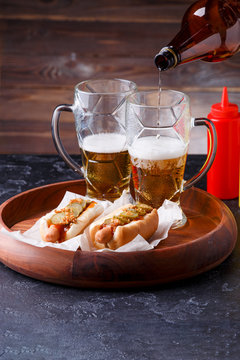 Image of two mugs of beer and hot dogs