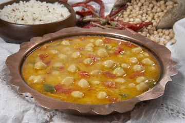 chickpeas in tomato sauce in a copper bowl closeup. horizontal
