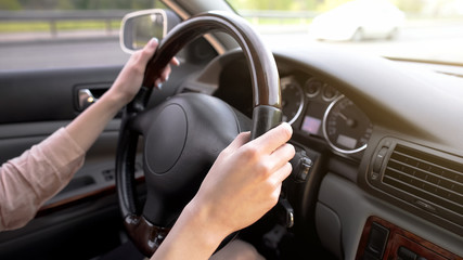 Female hands holding steering wheel, woman driving car, comfortable vehicle