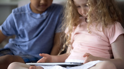 Fototapeta premium Couple of little multiethnic children playing in educational app on tablet