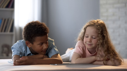 Afro-american boy shyly looking at pretty girl while watching show together