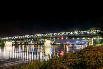 Bratislava, Slovakia May 23, 2018: Old bridge over river Danube in Bratislava at night with reflection in water, Slovakia, Europe.