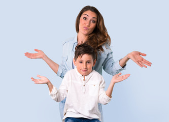Mother and daughter having doubts and with confuse face expression on blue background