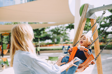 Portrait of adorable little boy having fun on swing at playground