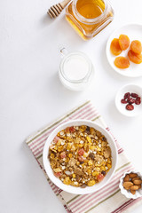 Muesli served with milk, honey, almonds, dried apricots and dried cranberries. Vertical shot. Flatlay.