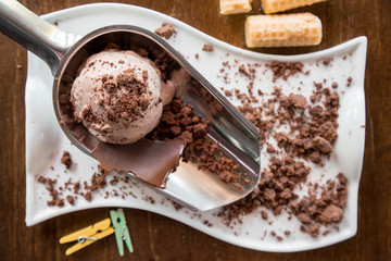 Plate of chocolate ice cream scoops with waffles on dark background, top view