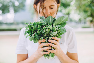 Young woman relaxing at summer picnic holding herbs