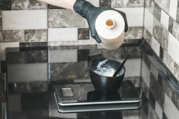 Hair stylist hands preparing a dye in a container