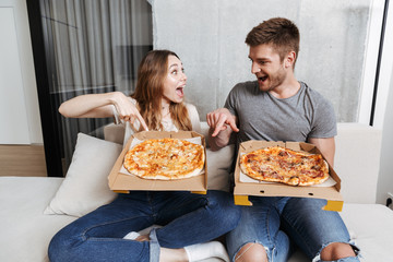 Cheerful young couple holding boxes with pizza