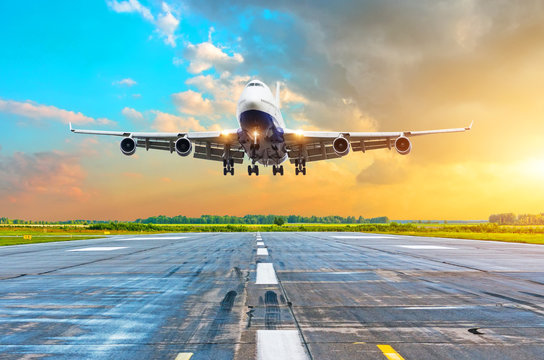 Aircraft With Four Engines Flying Arrival Landing On A Runway In The Evening During A Bright Red Gradient Sunset.