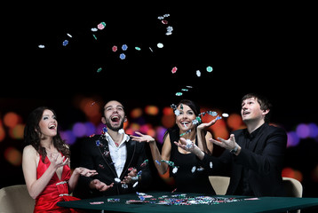 Group of young people playing poker at the gambling house
