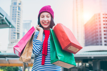 Portrait of an excited beautiful young girl wear shirt and wool hat holding many shopping bags and smile. With copy space. Woman shopper smiling happy. Beautiful young Caucasian. lifestyle, discount