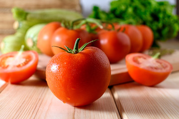 Close-up of fresh, ripe tomatoes with vegetables on wooden background.