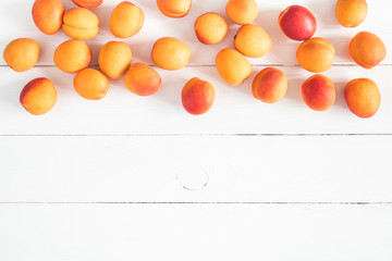 Fototapeta na wymiar Apricots on white wooden background. Flat lay, top view, copy space