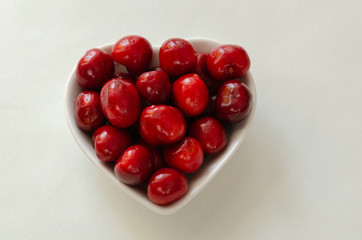 Fresh cherries in bowl on white background
